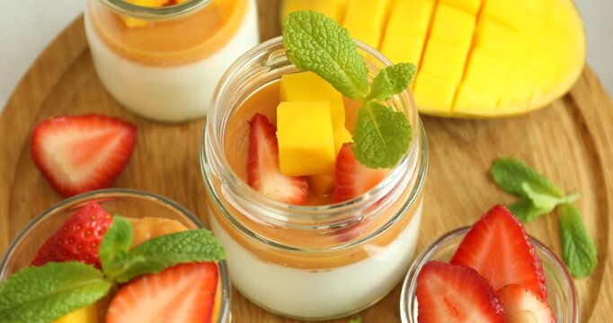 Delicious mango panna cotta, fruits and mint on table, above view