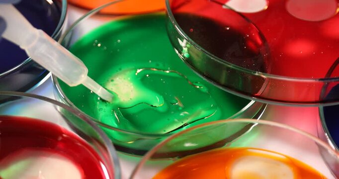 Scientist stirring sample in Petri dish at white table, closeup