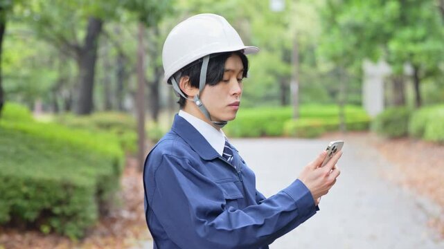 携帯を持つ作業着を着た男性