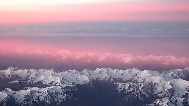 Aerial Andes scene shows ice covered summits, pink cloud layer, golden sunset rays. Airplane window frames Andean cordillera, snowcapped ridges under rose haze during twilight flight.