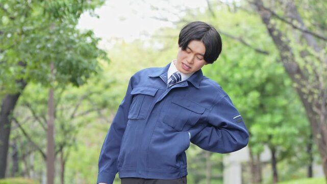 腰を痛める作業着を着た男性