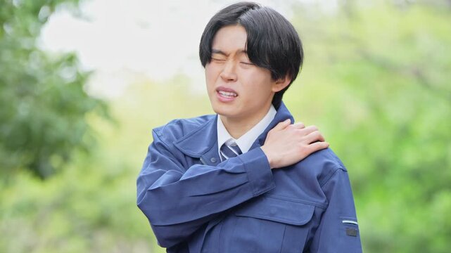 肩を痛める作業着を着た男性