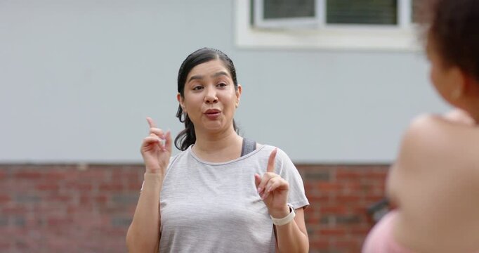 Adult woman answering partner cue, pointing outside home while fitness data appearing on watch
