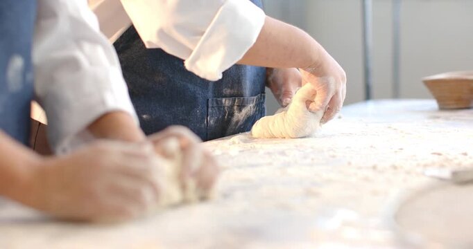 Diverse female bakers starting from rough dough, pressing and rolling at floured bench for baking