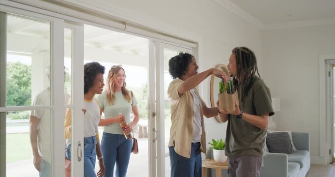Friends arriving host with dreads opening doors, handing drinks and hugging for party, copy space