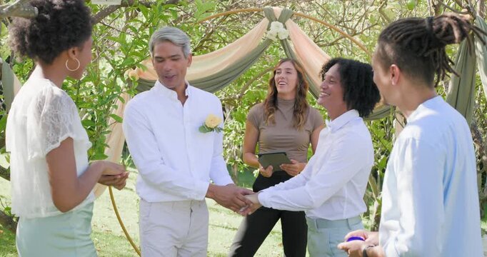 Diverse garden wedding party with attendants offering blue box gray partner placing ring to marry