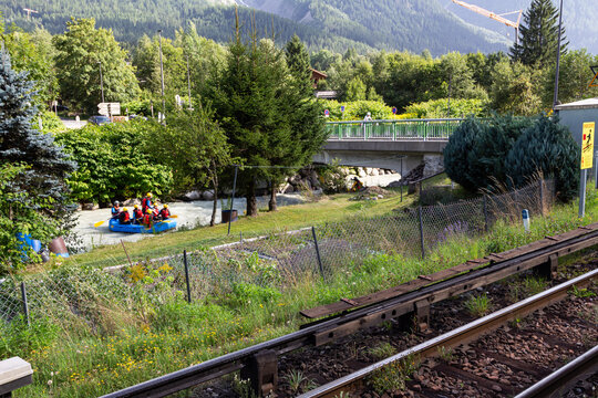 Chamonix-Mont-Blanc, Haute Savoie, France - August 09th, 2025: Sports enthusiasts practicing rafting on the Arve River, seen from the Les Pellerins train station operated by SNCF.