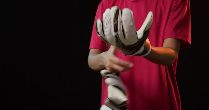 African American woman putting on gloves, fastening straps for match in studio, wearing red shirt