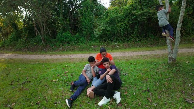 Mother and three sons resting on the grass enjoying a day at the park