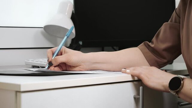 Doctor filling out medical documents and patient records during clinic visit administrative healthcare process and paperwork concept.