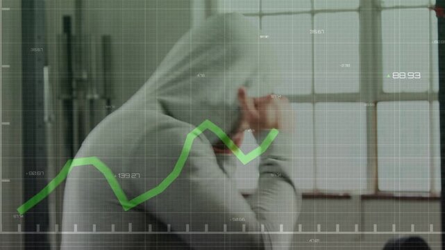Male athlete pulling hood and shadowboxing in gym by barbell, overlay graph syncing fitness metrics