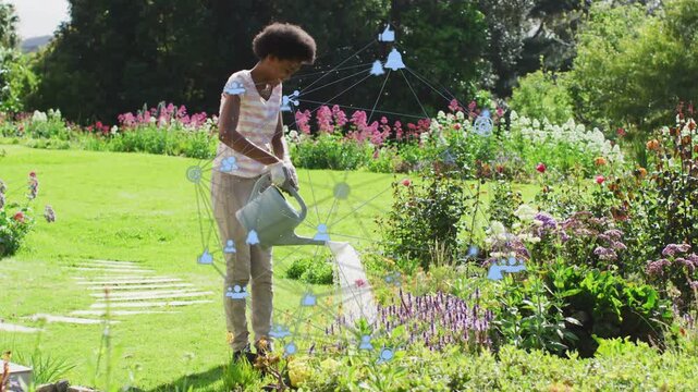 Teen girl tilting can, pouring water, stepping along bed and watering blooms with blue icon overlay