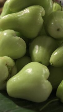 Vertical screen Green Rose Apples On Banana Leaf Vietnamese Street Market Stall Closeup Glossy Tropical Fruit Vendor Display Natural Light Fresh Harvest Texture Detail Shopper Atmosphere