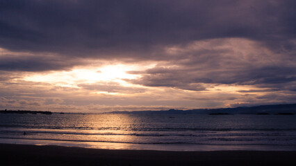 Obraz premium Beautiful golden sunset over the ocean with silhouettes of people swimming at Batu Bintang Beach, Sukabumi, Indonesia.
