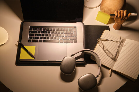 Desk with laptop, headphones, notebook, and glasses creating a productive study space