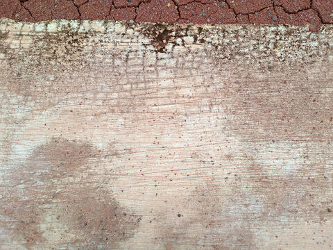 Weathered concrete surface with faded white paint and grime, bordered by red brick pavement urban grunge texture background