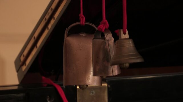 Close-up of rattles and a small bell, hanging from a red thread.