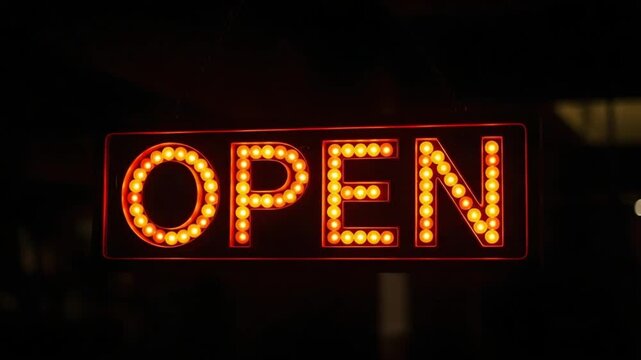 A bright orange open sign with lights on a dark background at night