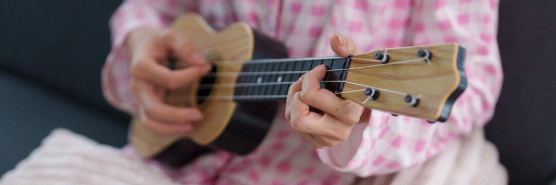 Person hands playing ukulele music practice home leisure activity developing skill learn musical instrument lifestyle content enjoyment