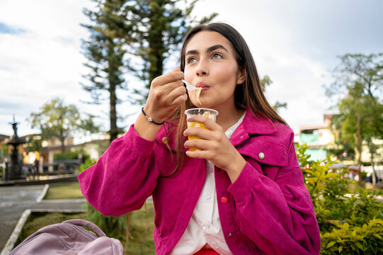 Latin woman enjoying a refreshing mango biche in a park in Latin America