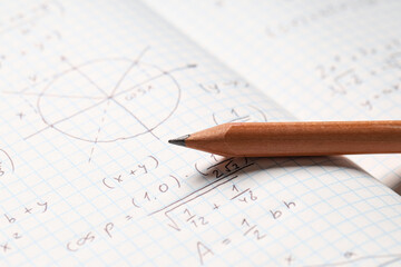 Fototapeta premium Copybook with handwritten maths formulas and pencil as background, closeup