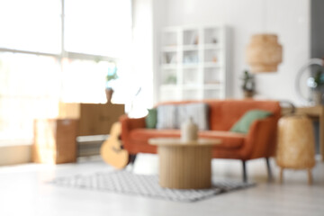 Fototapeta premium Interior of living room with brown sofa, coffee table, acoustic guitar and bicycle, blurred view