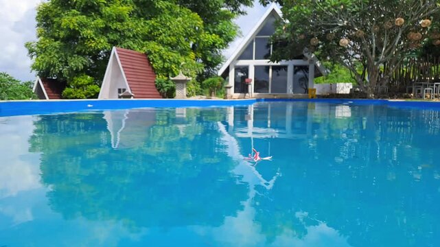 Cinematic shot of a scenic hilltop resort featuring various fun rides, a crystal-clear swimming pool, and a cozy cafe with a breathtaking mountain view. The footage highlights a traditional joglo.