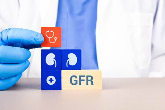 Concept of kidney health, nephrological screening, and global campaign for World Kidney Day. GFR. The nephrologist's hand arranges wooden cubes with kidney icons.