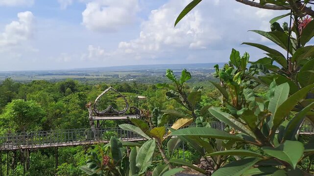 Cinematic shot of a scenic hilltop resort featuring various fun rides, a crystal-clear swimming pool, and a cozy cafe with a breathtaking mountain view. The footage highlights a traditional joglo.