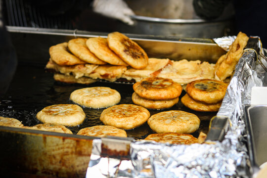 A street food stall featuring freshly made hotteok, popular Korean pancakes, sizzling on a large metal griddle.