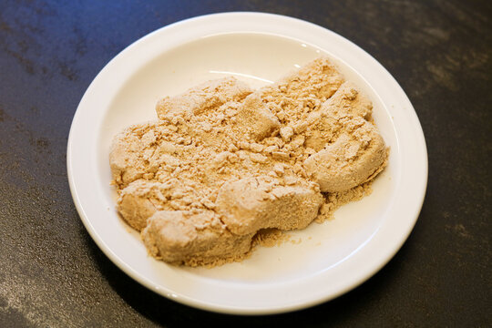 Traditional chewy rice cakes dusted with soybean powder, served on a white dish.