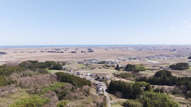 Aerial drone view of Sendai plain and Pacific coastline in Japan, wide rural landscape under clear sky