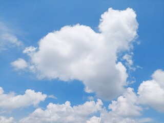 Fototapeta premium Blue sky background with soft floating clouds. Peaceful and serene summer sky with fluffy white clouds.