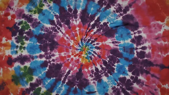 Vibrant rainbow tie dye spiral pattern on fabric background for creative summer fashion and retro designs.