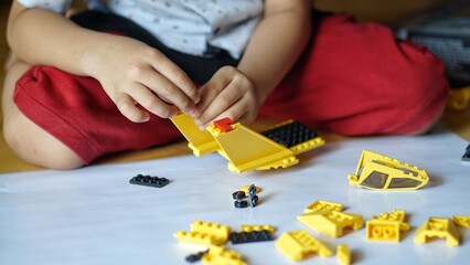 Obraz premium Close up of child's hands playing with colorful plastic bricks or lego. Toddler having fun and building out of bright constructor bricks. Development toys