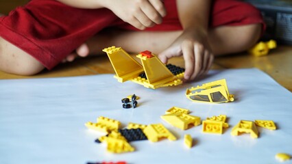 Obraz premium Close up of child's hands playing with colorful plastic bricks or lego. Toddler having fun and building out of bright constructor bricks. Development toys