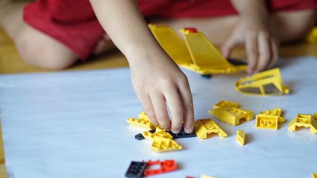 Close up of child's hands playing with colorful plastic bricks or lego. Toddler having fun and building out of bright constructor bricks. Development toys