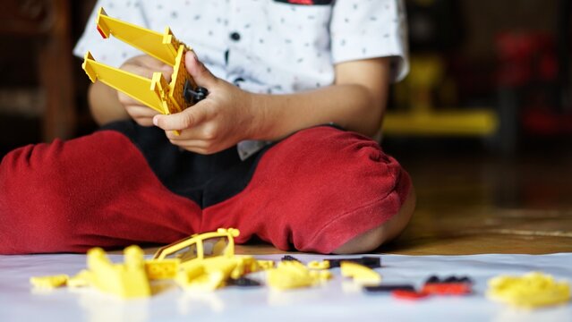 Close up of child's hands playing with colorful plastic bricks or lego. Toddler having fun and building out of bright constructor bricks. Development toys
