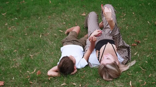 Parental love. Peaceful summertime. Happy mother contented son enjoying playful fun in lush green park carefree leisure talking outdoor.