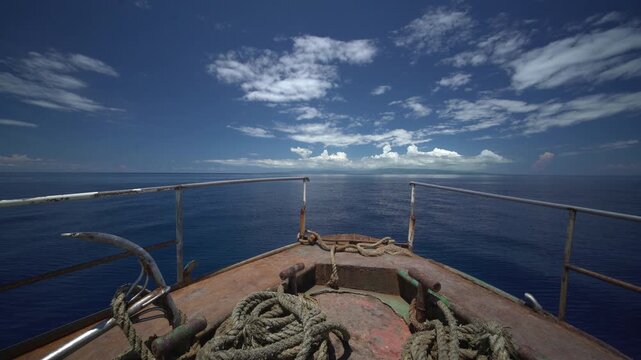 Point of view from boat bow sailing across calm Pacific Ocean with smooth water and wide horizon under clear sky peaceful travel concept