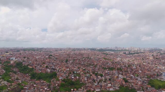 High angle drone shot of an informal settlement in Salvador, Brazil, highlighting the red brick architecture and coastal horizon.