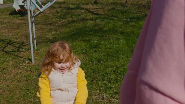 Redheaded girl playing on seesaw at playground. Happy female child having fun on teeter totter outdoors. Childhood activity, leisure time, recreation in park.