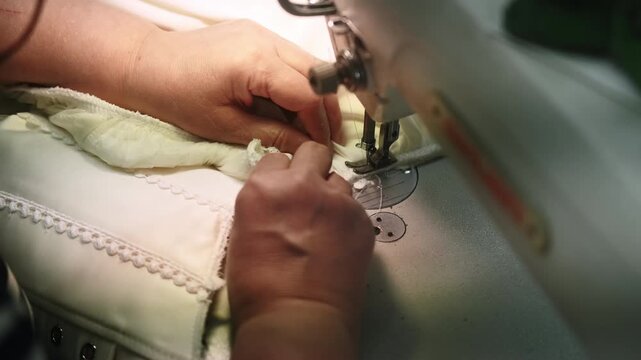 Clothing production. Tailor process. Hand sewing white corset dress on professional stitching machine. Manufacturing industry technique.