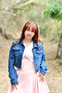 Retrato de una mujer joven hispana, vestida con una chaqueta color azul y un vestido color rosado, concepto de moda y estilo al aire libre.