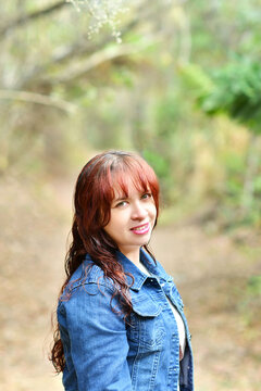 Mujer joven hispana, vestida con una chaqueta color azul, concepto de moda y estilo al aire libre rodeado de naturaleza.