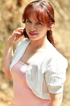 Chica latina con un rostro muy bello, ojos verdes, usando un vestido color rosa y una chaqueta blanca. Concepto de moda y estilo.