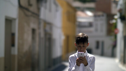 Obraz premium Happy boy in the alley is looking at the phone, have fun and enjoy