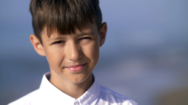 Portrait of a boy who squint from the sun and looks into the camera, have fun and enjoy