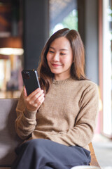 Fototapeta premium Vertical portrait image of a woman holding and using mobile phone in cafe