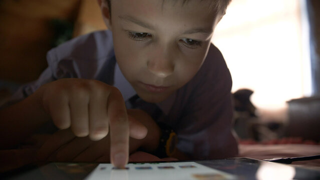 boy lays in a bed and touches on a tablet PC at home, have fun and enjoy